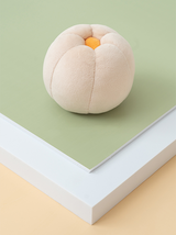 Plush peach toy on a green and beige background