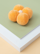 Plush toy resembling a flower on a green and white surface